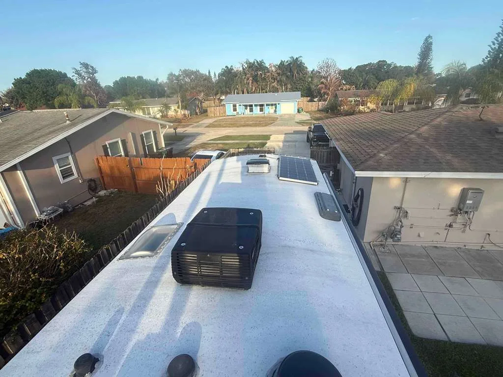 Tidepool RV technician replacing a rooftop AC unit on an RV at a Florida campground