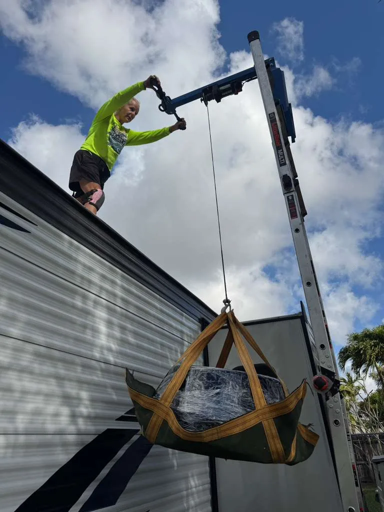 Lifting a new Dometic Brisk II AC unit onto an RV roof for replacement
